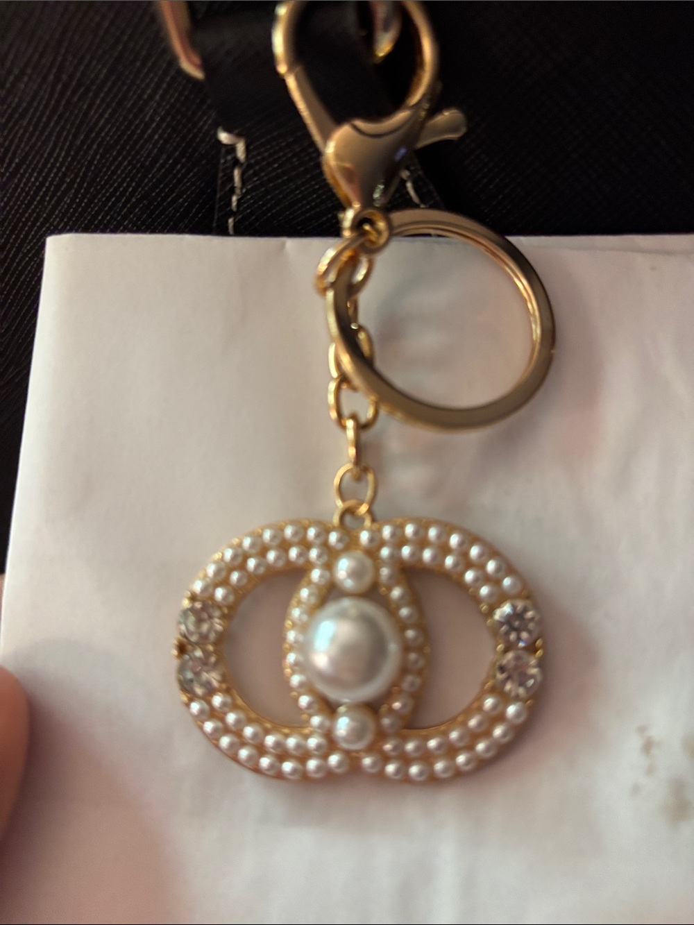 gold-toned handbag charm featuring a simulated pearl and rhinestone "OO" design